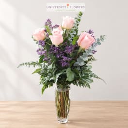 Pink roses and purple filler flowers in a clear glass vase