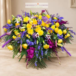Large mixed bouquet of yellow, purple, and white flowers in a low container