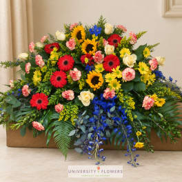 Large mixed flower arrangement with sunflowers, gerbera daisies, roses, and blue accents