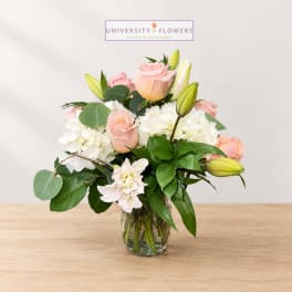 Pink roses and white lilies arranged in a clear glass vase