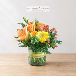 Orange lilies and yellow gerbera daisies in a glass vase