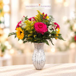 Pink roses and yellow sunflowers arranged in a white vase