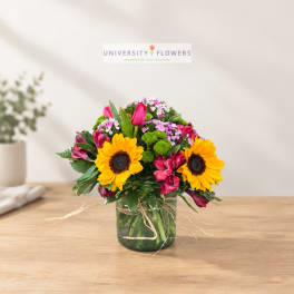 Mixed bouquet with sunflowers and pink alstroemeria in a glass vase