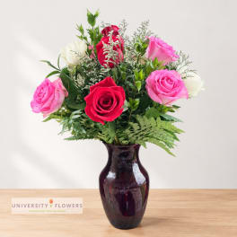 Mixed roses in a dark glass vase on a wooden surface