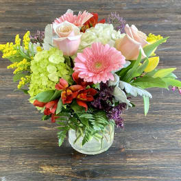 Mixed bouquet of pink roses, gerbera daisies, and hydrangeas in a glass vase