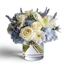 White roses and lilies with blue hydrangeas in a glass vase