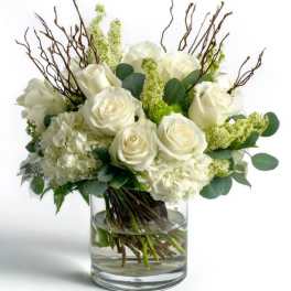 White roses and hydrangeas in a glass vase with branches