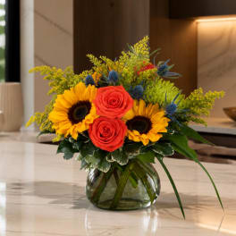 Sunflowers and red roses arranged in a glass vase