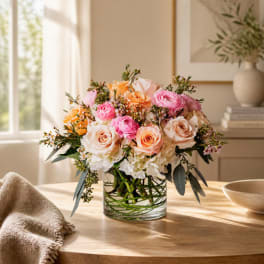Pink and peach roses arranged in a clear glass vase on a table