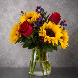 Bouquet of sunflowers and red roses in a clear glass vase