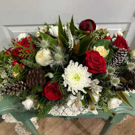 Red and white floral arrangement with pinecones in a low container