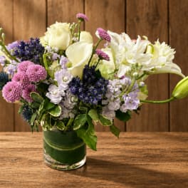 Mixed bouquet of white, pink, and lavender flowers in a glass vase