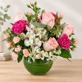 Pink roses and white alstroemeria in a green glass vase