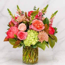 Mixed pink and coral flowers arranged in a clear glass vase