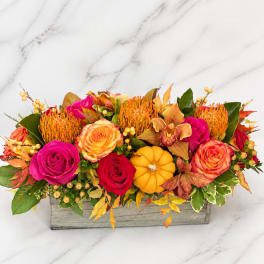 Autumn floral arrangement with roses, orchids, and a small pumpkin in a wooden box