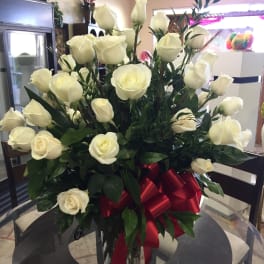 Bouquet of white roses in a clear glass vase with a red ribbon