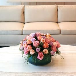Pink and lavender rose arrangement in a low round container