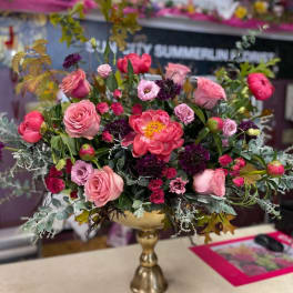 Pink and purple floral arrangement in a gold pedestal vase