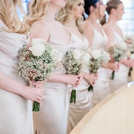 Bridesmaids holding small white rose bouquets