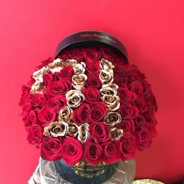 Large bouquet of red and gold roses in a black hatbox