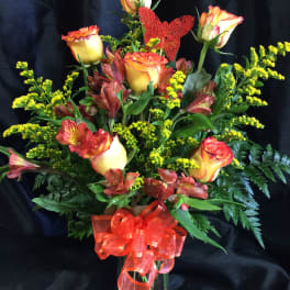 Bouquet of orange-yellow roses and red alstroemeria in a glass vase