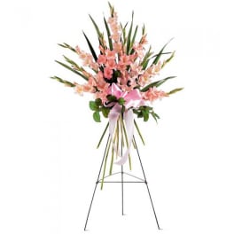 Pink floral standing spray on an easel with a ribbon bow