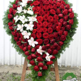 Heart-shaped wreath of red roses with white orchids on an easel