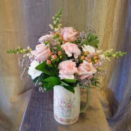 Pink roses and carnations in a rabbit-print pitcher vase