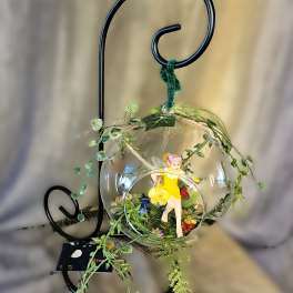 Glass ornament with a small fairy figure and tiny flowers on a black metal stand