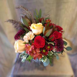 Bouquet of red and cream roses with purple mums in a vase