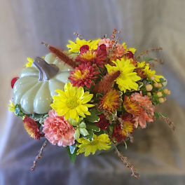 Autumn bouquet with yellow and pink flowers beside a decorative pumpkin