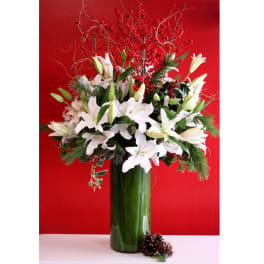 White lilies in a tall green vase with red berry branches
