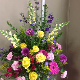 Tall mixed bouquet with yellow roses, pink gerberas, and purple flowers in a vase