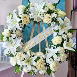 White floral wreath on an easel with a "Loving Memory" ribbon