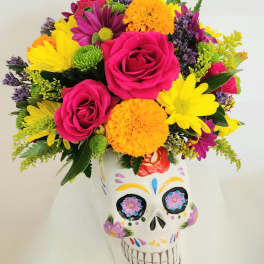Colorful bouquet of roses and daisies in a painted skull vase