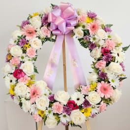Floral wreath with pink ribbon on a wooden stand