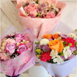 Three mixed flower bouquets in pink, lavender, and white wrapping