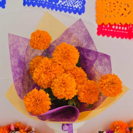 Orange marigold bouquet wrapped in purple and yellow paper