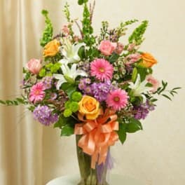 Mixed bouquet of pink, orange, white, and purple flowers in a glass vase