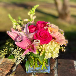 Pink roses, lilies, and hydrangea in a square glass vase