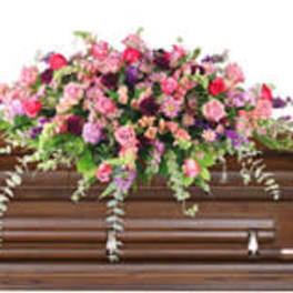 Large pink and purple floral spray on a wooden casket