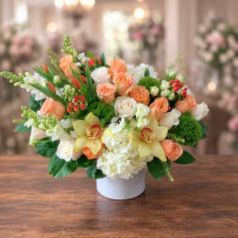 Peach and white floral arrangement in a white vase