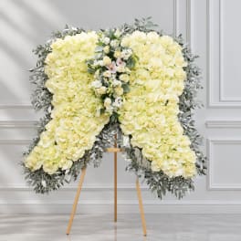 Large white rose funeral spray on an easel with greenery