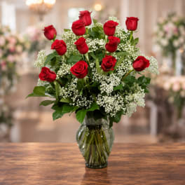 Red roses arranged in a clear glass vase with white baby's breath