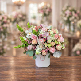 Pink and white floral arrangement in a white cylindrical vase