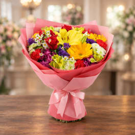 Mixed bouquet of colorful flowers wrapped in pink paper with a ribbon