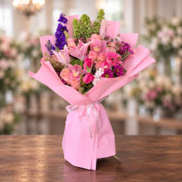 Pink bouquet with lilies, roses, tulips, and purple flowers wrapped in pink paper