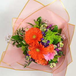 Bouquet of orange gerbera daisies and mixed flowers wrapped in pink paper