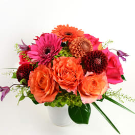 Bouquet of orange and pink flowers in a white vase