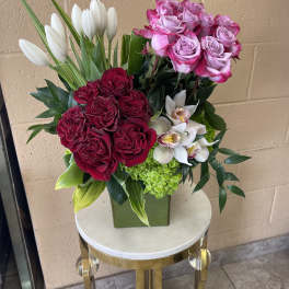 Mixed bouquet of pink and red roses with white tulips in a square vase